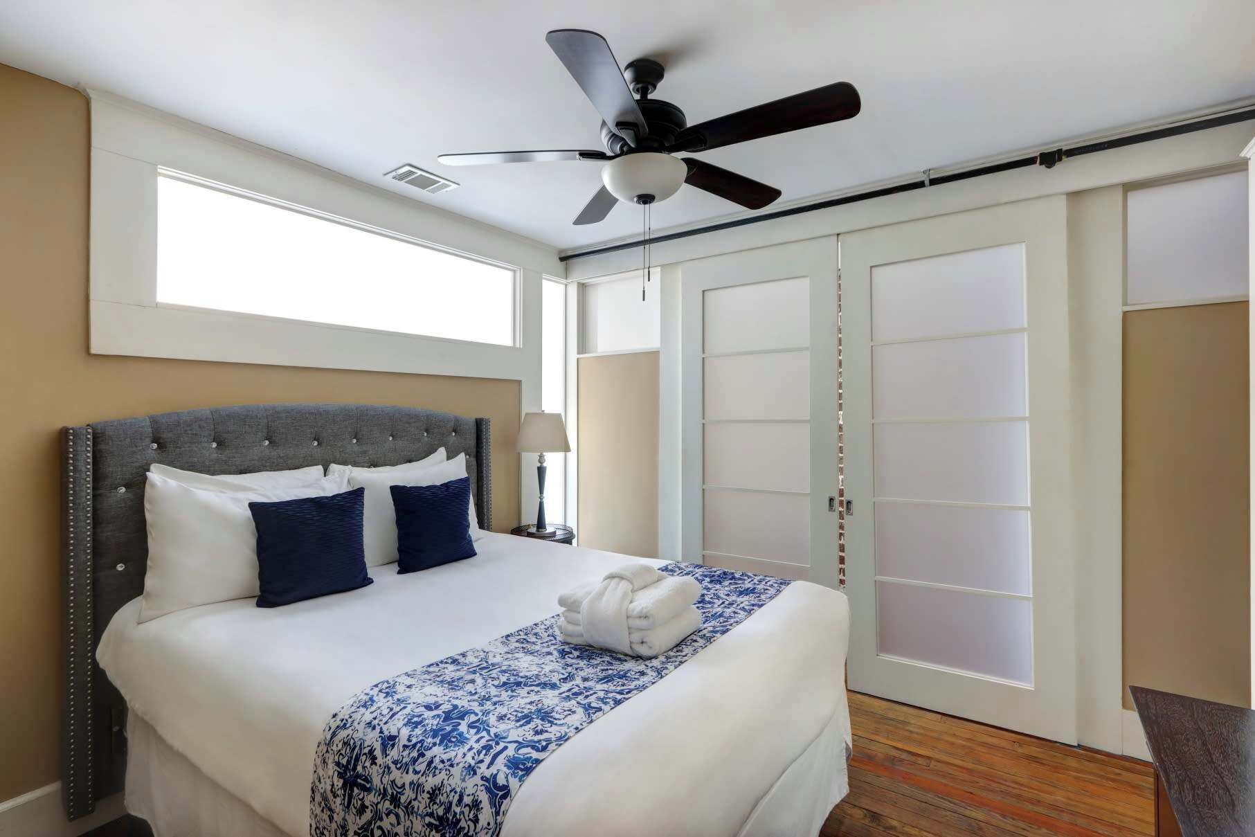 Ein Hotelzimmer mit einem Bett, einem Deckenventilator, einem Fenster und einer Schiebetür.