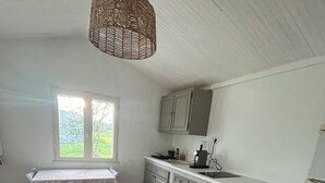 A kitchen with white cabinets, a dining table, and a hanging light fixture. - Charmant Cabanon Provençal (Montfort-sur-Argens)