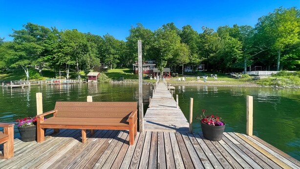A wooden pier extending into a lake, with a bench and potted flowers at the end. - Big Pines at the Lake -  waterfront  - swimming, fishing, boating (Cooperstown)