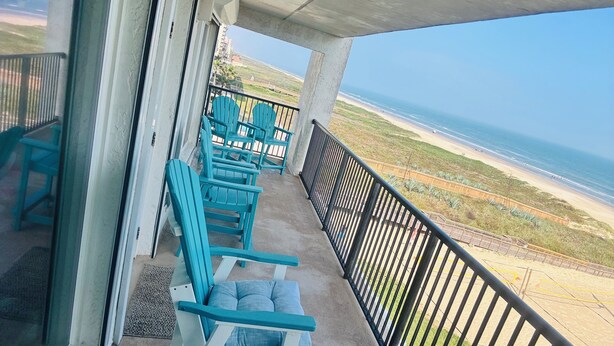 A balcony with blue chairs and a view of the beach and ocean. - Panoramic Ocean Front view 3 bedroom 3 bath condo
STR License 2024-0443 (South Padre Island)