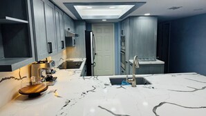 A modern kitchen with a marble countertop, built-in appliances, and recessed ceiling lighting. - Panoramic Ocean Front view 3 bedroom 3 bath condo
STR License 2024-0443 (South Padre Island)