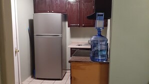 Une cuisine compacte équipée d’un réfrigérateur, d’un distributeur d’eau et d’un évier.