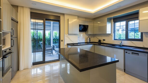 A modern kitchen with a large island, stainless steel appliances, and a sliding glass door leading to a patio. - Villa Tutar Icmeler Daily Weekly Rentals (Marmaris)