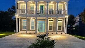 A two-story house with a balcony on the second floor, a green door, and a number "402" on the front door. - The Quiet Storm - Walk to Beach - 4BR/3BA - 3 Living Areas (North Myrtle Beach)