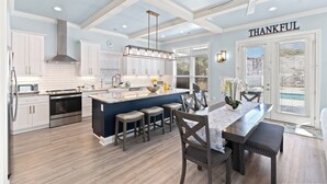 A spacious kitchen with white cabinetry, a central island with stools, and a ceiling fan. - The Quiet Storm - Walk to Beach - 4BR/3BA - 3 Living Areas (North Myrtle Beach)