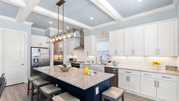 A modern kitchen with white cabinetry, a large island with bar stools, stainless steel appliances, and a pendant light fixture. - The Quiet Storm - Walk to Beach - 4BR/3BA - 3 Living Areas (North Myrtle Beach)