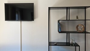 Ein modernes Wohnzimmer mit einem flachbildfernseher an der Wand, einer schwarzen Unterhaltungsanlage mit Regalen und einem Couchtisch.