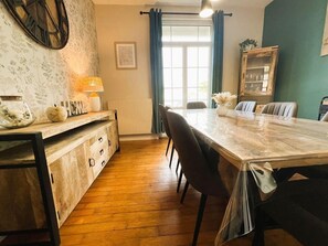 Un coin repas avec une table en bois, des chaises, une lampe et une vue sur l’extérieur.