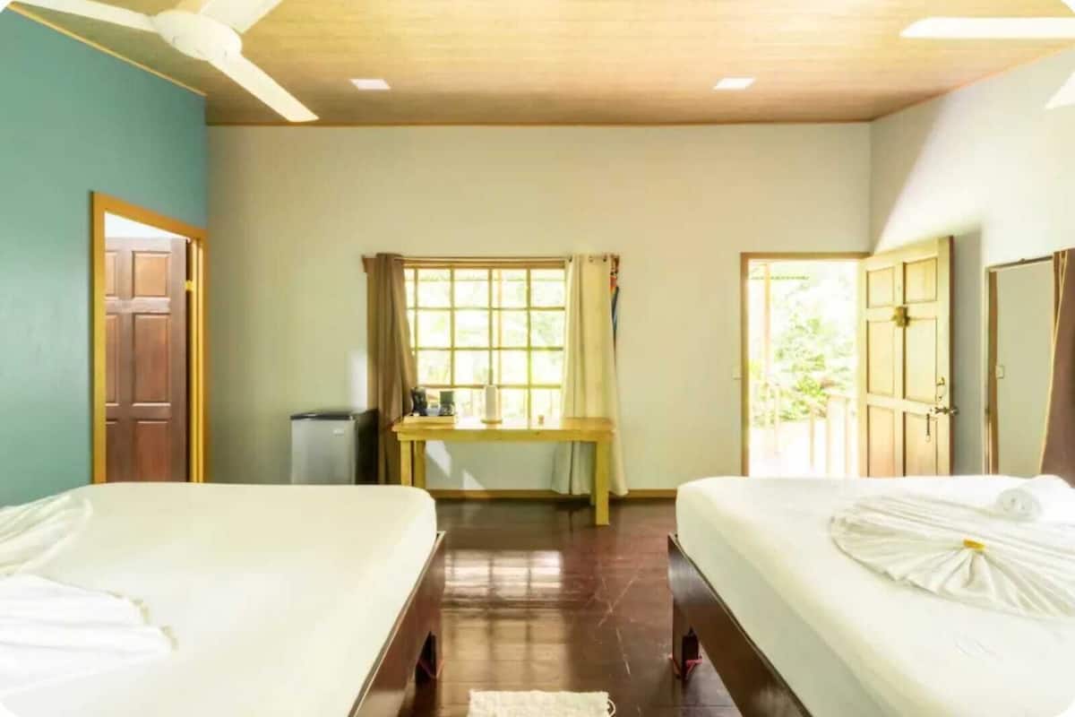 A room with two beds, a desk, and a window with curtains.