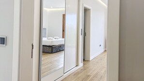 Een moderne hotelkamer met een grote schuifdeur naar een slaapkamer, compleet met een bed en een houten vloer.