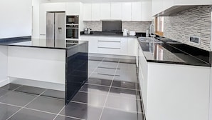 Een moderne keuken met witte kastjes, zwarte aanstootplaten en een betegelde spatwand.