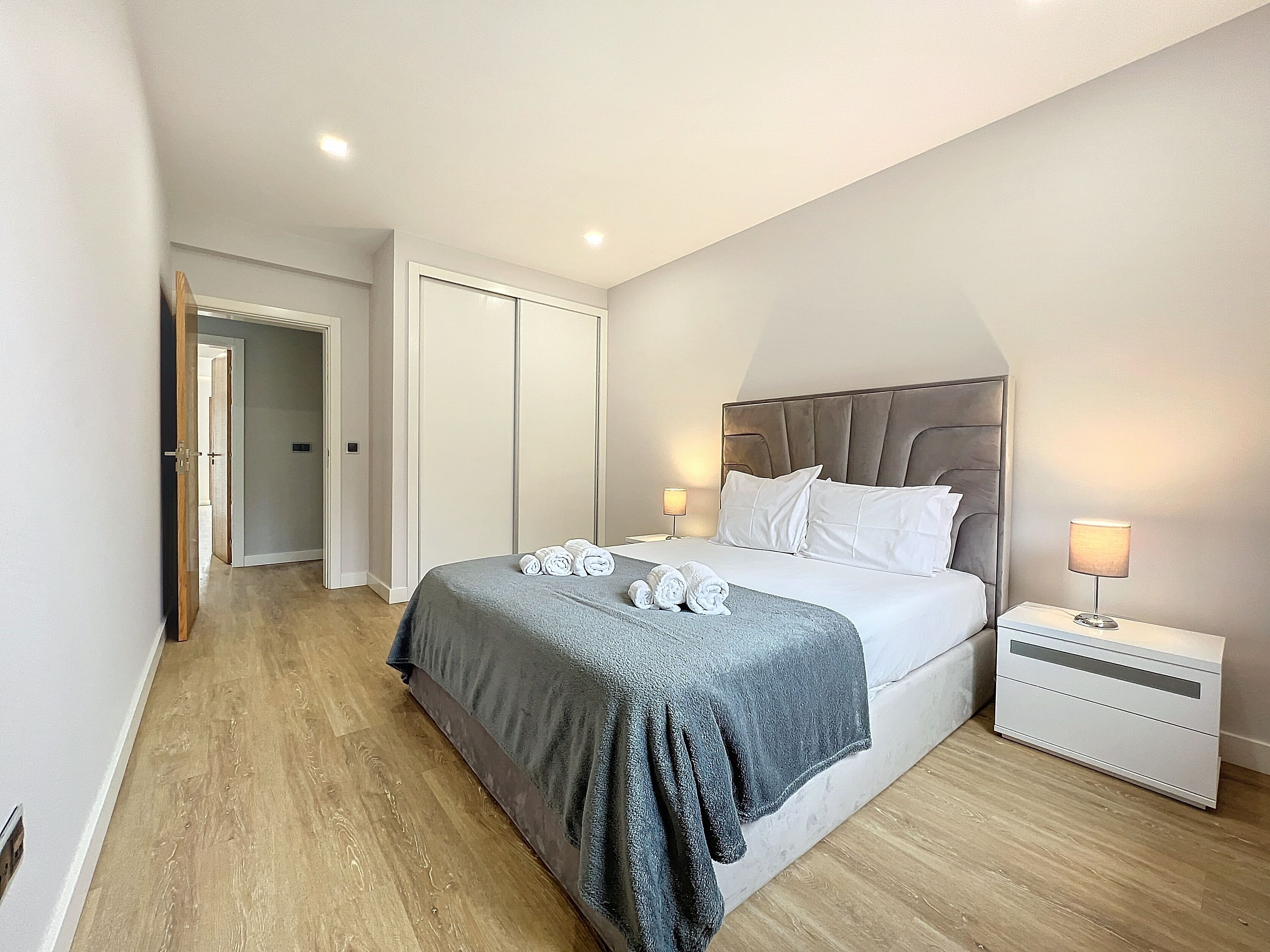 Una camera da letto moderna con un letto grande, un comodino e una cabina armadio.