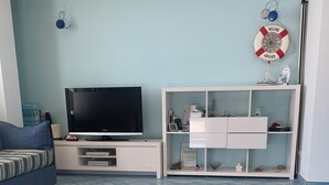 A living room with a flat-screen TV, a sofa, a white entertainment unit, and a patterned floor runner. - Pizzo, Costa Degli Dei - Terrazza Sul Mare (Pizzo)