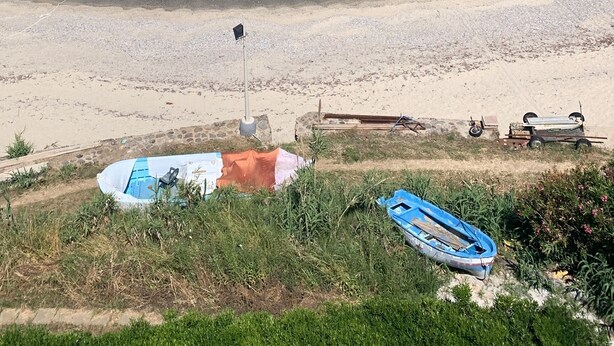 A beach with clear turquoise waters, a rocky breakwater, and a few boats on the shore. - Pizzo, Costa Degli Dei - Terrazza Sul Mare (Pizzo)