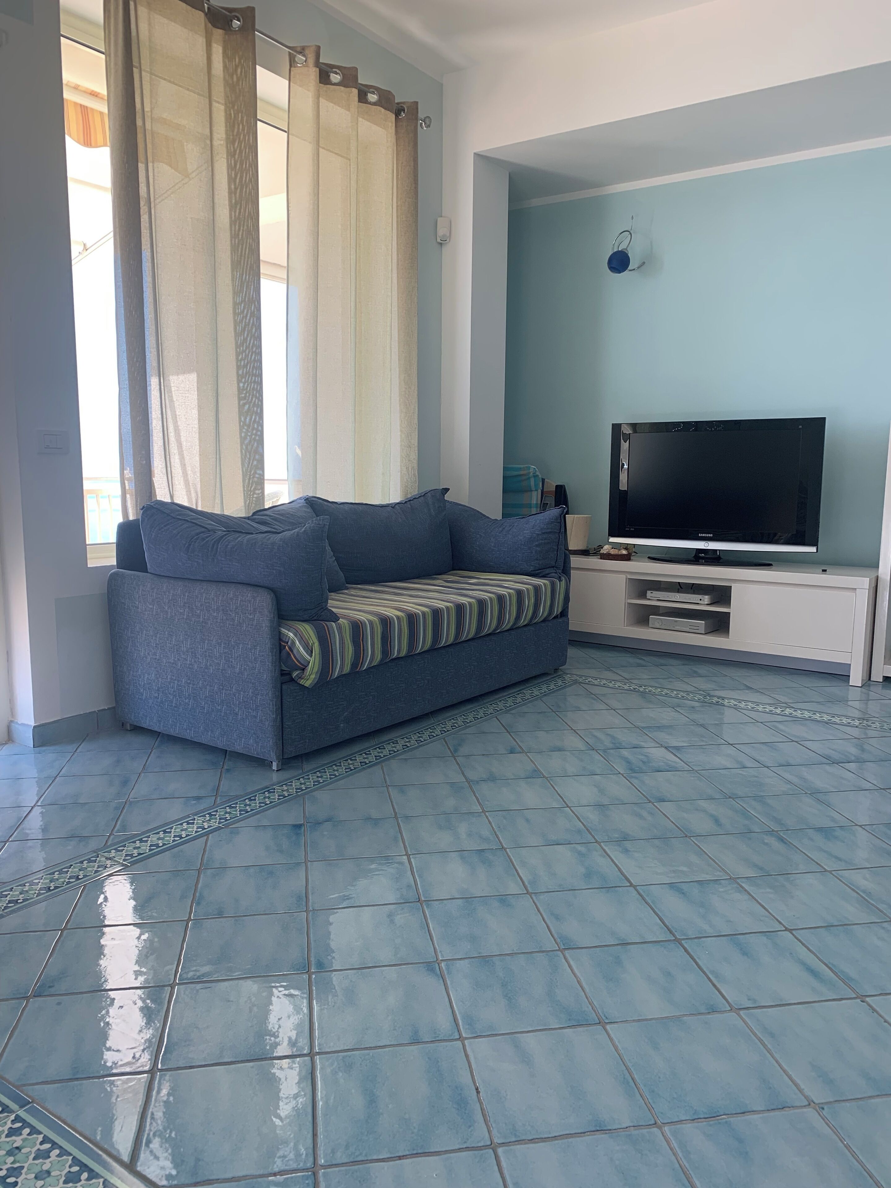 A living room with a sofa, a TV, and a window with curtains.