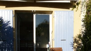 Un patio al aire libre con una mesa y sillas de madera, una puerta corrediza y piso de baldosas.