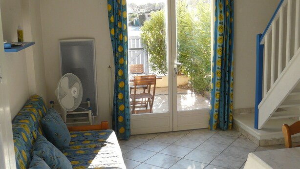 Una habitación con cama, ventilador, mesa y una escalera.