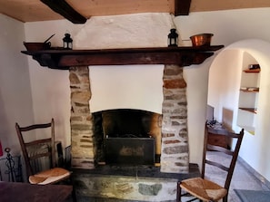 Cozy room features a traditional stone fireplace with a mantel, two chairs, and a small table.