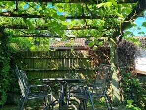 Relax under the shade of a pergola surrounded by lush greenery and enjoy dining or relaxation at this serene outdoor space.