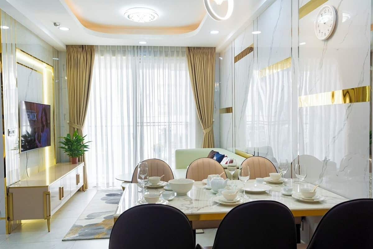 A modern dining room with a marble table, chairs, and a television on a cabinet.