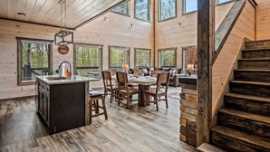 A spacious kitchen with a central island, large windows, and a staircase leading to upper levels. - Spacious 4BD Lodge w/ POOL! Hot Tub + Theater Room (Sevierville)