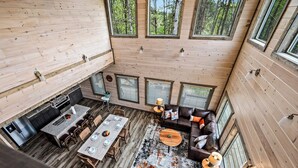 A spacious cabin interior with a dining area, a sofa, and a fireplace. - Spacious 4BD Lodge w/ POOL! Hot Tub + Theater Room (Sevierville)