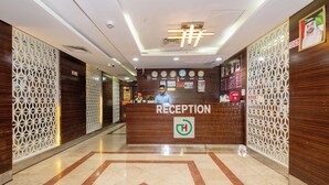 Un'area reception con scrivania in legno, una sveglia e un cartello che indica la presenza di un defibrillatore.