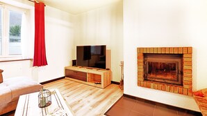 A living room with a TV, fireplace, and wooden flooring.