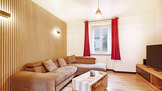 A modern living room with a sectional sofa, a wooden coffee table, and a flat-screen TV.