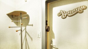 A door with a 'Bienvenue' sign and a coat rack with multiple hooks.