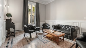A living room with a dark leather sofa, a wooden coffee table, and a small side table. - L'Ostal de Pomérols - Grande maison pour 10 (Pomérols)