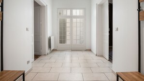 A hallway with a double door, white walls, and a tiled floor. - L'Ostal de Pomérols - Grande maison pour 10 (Pomérols)