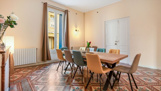 A dining area with a wooden table, six chairs, and a patterned floor. - L'Ostal de Pomérols - Grande maison pour 10 (Pomérols)