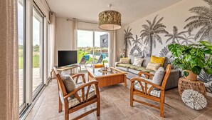 A spacious living room with a large TV, comfortable seating, a coffee table, and a view of the outdoors. - Le 101 - Plage du Dossen à Santec à 1.5 km (Santec)