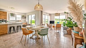 A spacious kitchen with a dining area, large windows, and a view of the outdoors. - Le 101 - Plage du Dossen à Santec à 1.5 km (Santec)