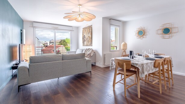Een moderne woonkamer met een bank, een eettafel voor vier personen en een groot raam met uitzicht op het landschap.