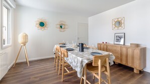 Een eethoek met een lange houten tafel, stoelen en een buffetkast.