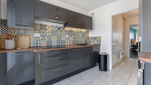 Een moderne keuken met donkere kastjes, een decoratieve achterwand en een houten aanrecht.