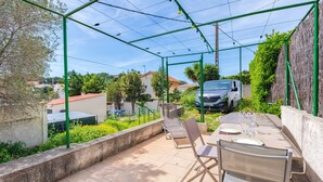 An outdoor patio with a table and chairs, surrounded by a green metal pergola.