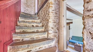 A stone staircase leading to a room with a blue sofa and a small table. - Augustine Beach - Maison à 700 m de la plage (Courseulles-sur-Mer)