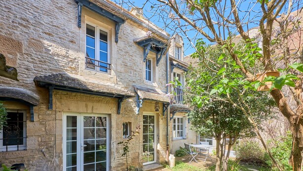A stone building with a wooden deck and a small garden area. - Augustine Beach - Maison à 700 m de la plage (Courseulles-sur-Mer)