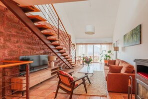 A spacious living area with a brick wall, wooden staircase, and a cozy seating arrangement. - Le Cerisier - Bel Appt pour 4 personnes (Puberg)