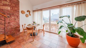 Un comedor con una mesa redonda, sillas de madera, una planta en maceta y una pared de ladrillo.