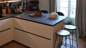A modern kitchen with a central island, bar stools, and a view of the city through large windows. - Magnifique Appartement Plein Centre Nice. 170 m2, 4 cc, 3sdb, Deux pas de Tout (Nice)