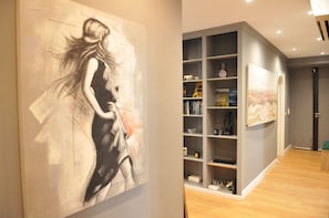 A modern interior with a large abstract painting, a bookshelf, and a door.