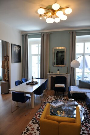 A modern living room with a dining area, a fireplace, and a large window.