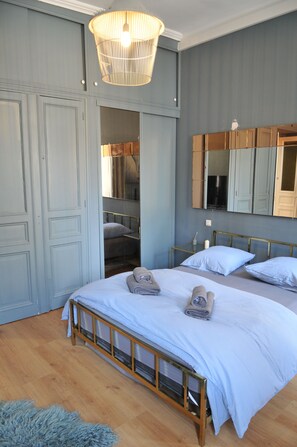 Une chambre à coucher comprenant un lit, une armoire, un miroir et un luminaire suspendu.