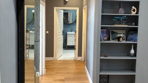 A hallway with a mirrored wardrobe, a shelf with decorative items, and a kitchen visible through an open door. - Magnifique Appartement Plein Centre Nice. 170 m2, 4 cc, 3sdb, Deux pas de Tout (Nice)