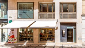 A modern building with a glass storefront displaying shoes. There is a white awning over the entrance, and a sign indicating a fire exit. - Great private terrace in the heart of the city centre  (Málaga)