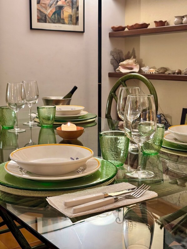 Une table à manger dressée avec de la verrerie verte, des assiettes blanches à bordure jaune et un pichet en verre transparent.